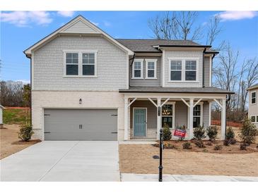 Charming two-story home featuring a welcoming front porch and a gray two-car garage at 5060 Trescott Path, Cumming, GA 30028