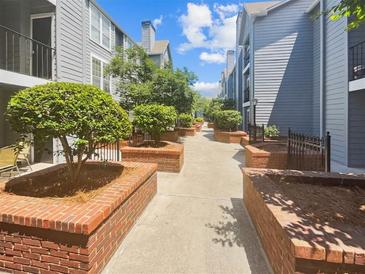 Charming condo courtyard featuring landscaped brick planters and mature trees along walking path at 311 Granville Ct, Atlanta, GA 30328