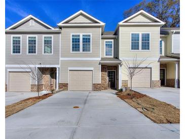 Charming townhouse with attached garages, brick accents and manicured lawns, set against a bright blue sky at 6104 Ripple Way # 50, South Fulton, GA 30349
