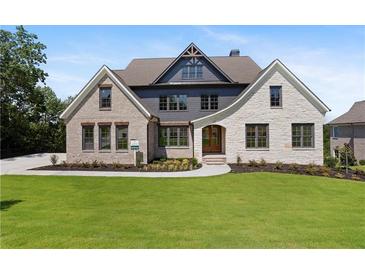 Two-story home with brick and stone accents, and a lush green lawn at 5693 Brendlynn Dr, Suwanee, GA 30024