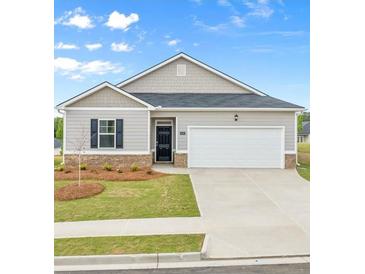 Charming single-story home featuring a manicured lawn, two-car garage, and classic architectural details at 8593 Preakness Pass, Lithonia, GA 30058