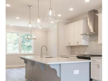Bright kitchen features white cabinets, stainless appliances, and pendant lighting above the island at 1956 Deco Dr, Kennesaw, GA 30144