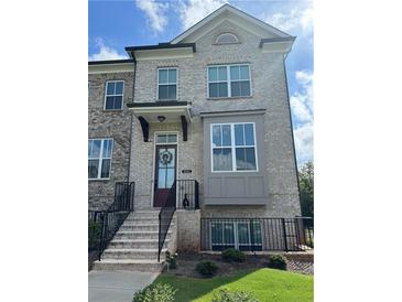 Beautiful townhome with brick facade, adorned with a welcoming wreath, and a well-maintained front yard at 4440 Sims Park Overlook, Suwanee, GA 30024