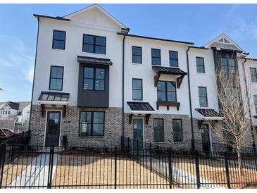 Townhome exterior features brick accents, black trim, and a white facade at 629 Silva St # 128, Cumming, GA 30040