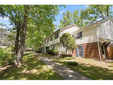 Traditional-style home featuring a brick facade and symmetrical design with mature trees in a landscaped yard at 6584 Sleepy Hollow Ln, Morrow, GA 30260