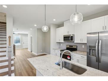 Bright kitchen features stainless appliances, white cabinets, granite countertops, and modern globe pendant lights at 1095 Tucker Ave # 401, Atlanta, GA 30310