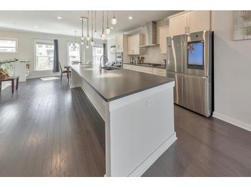 Spacious kitchen with large island, stainless steel refrigerator and modern pendant lighting at 550 Whitlox Nw Rd, Atlanta, GA 30318