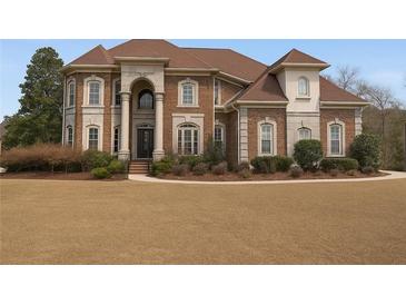 Elegant brick home featuring a manicured front lawn and stately architectural details at 4850 Guilford Forest Sw Dr, Atlanta, GA 30331