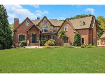 Elegant brick and stone home with manicured lawn and mature landscaping offers luxurious curb appeal at 2145 Jones Phillips Rd, Dacula, GA 30019