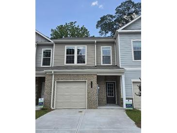 Charming two-story townhome featuring a one-car garage and neutral-tone siding with stone accents at 6202 Ripple Way # 88, South Fulton, GA 30349