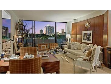 Elegant living room featuring floor-to-ceiling windows with city views, wood paneling, and stylish contemporary furnishings at 2575 Peachtree Ne Rd # 14A, Atlanta, GA 30305