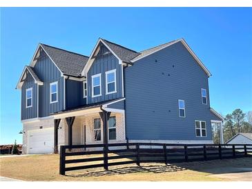 Beautiful two-story home featuring navy siding, white brick accents, and a charming covered porch at 738 Crossroad Ct, Powder Springs, GA 30127