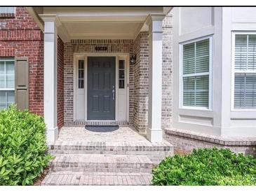 Charming brick home entry featuring a gray front door, white columns, and lovely landscaping at 2382 Gallard St, Lawrenceville, GA 30043