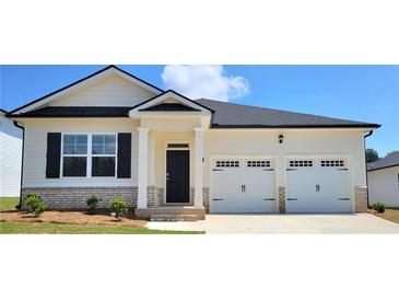 Charming single-story home with a two-car garage, brick accents, and a well-manicured lawn at 134 Oakchase Park Ln, Hampton, GA 30228