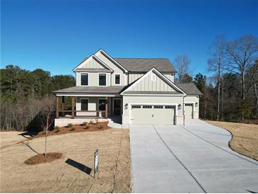 Two-story house with three-car garage, covered porch, and landscaping at 1129 Red Oak Blvd, Loganville, GA 30052