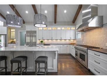 Bright kitchen features white cabinets, marble counters, a stainless hood, dark floors and wood beam details at 2908 Mabry Ne Ln, Brookhaven, GA 30319