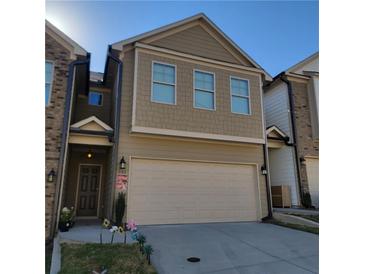 Tan three-story townhome with attached garage and landscaping at 243 Beau St, Lilburn, GA 30047