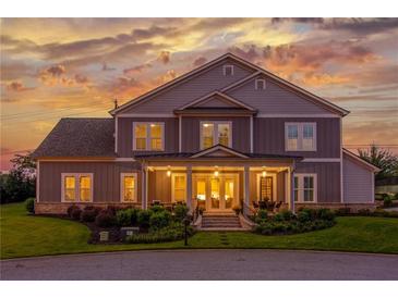 Charming two-story home with a welcoming front porch and beautifully landscaped front yard at sunset at 5629 Vineyard Park Trl, Norcross, GA 30071