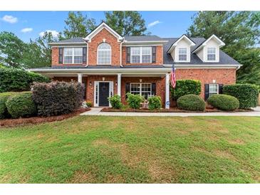Charming two-story red brick home featuring a well-manicured lawn and inviting front porch with classic columns at 1500 Terminal Ct, Mcdonough, GA 30252