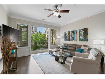Bright living room featuring a leather sectional, ceiling fan, and access to the balcony at 3621 Vinings Slope Se # 3411, Atlanta, GA 30339