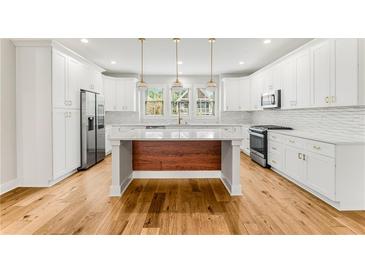 Bright kitchen with white cabinets, stainless steel appliances, wood floors, and an island with wood accents at 370 Thrasher St # 2, Norcross, GA 30071