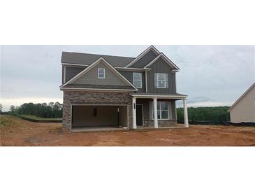 Two-story home featuring a stone facade, an attached garage, and covered front porch at 5994 Spring Way, Stonecrest, GA 30038