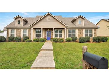 Charming brick home boasts a well-manicured lawn and inviting blue front door at 1129 Abundance Dr, Locust Grove, GA 30248