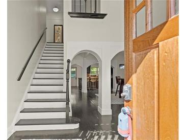 Elegant foyer with an open staircase, dark wood floors, and arched doorways leading to other rooms at 7445 Talbot, Sandy Springs, GA 30328