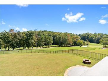 Expansive lawn with iron fence overlooks a golf course and woods at 8150 Albritton Downs, Cumming, GA 30041