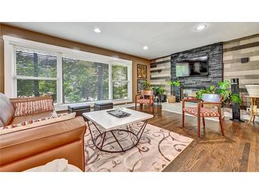 Inviting living room featuring hardwood floors, a stone fireplace, and large window providing ample natural light at 2953 Collier Nw Dr, Atlanta, GA 30318