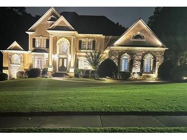 Elegant two-story home with stone accents and manicured lawn at night at 2330 Blackheath Trce, Alpharetta, GA 30005