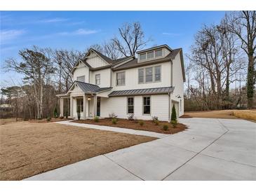 Beautiful two story home with white siding, metal roof, landscaped front yard, and concrete driveway at 1697 Eastside Parc St, Atlanta, GA 30316