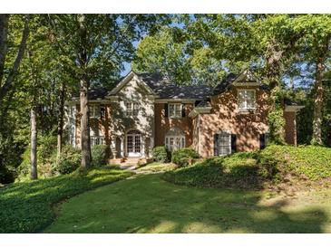 Charming brick home with a landscaped front yard nestled amongst mature trees in a quiet neighborhood at 940 Waters Reach Ct, Alpharetta, GA 30022