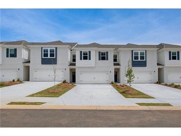 Charming townhomes featuring brick, white siding, garages, and well-manicured landscaping at 212 Sanctuary Drive, Mcdonough, GA 30253