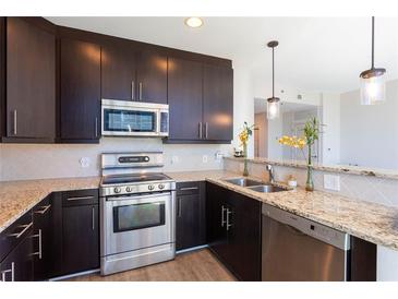 Modern kitchen with stainless steel appliances, granite countertops, and stylish lighting fixtures at 1080 Peachtree Ne St # 1408, Atlanta, GA 30309