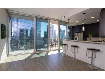 Bright living room featuring a breakfast bar, hardwood floors, and sliding glass doors to a balcony with city views at 1080 Peachtree Ne St # 1408, Atlanta, GA 30309