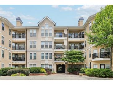 Condo building with multiple units, balconies, black railings, beige exterior, and manicured landscaping at 1850 Cotillion Dr # 3221, Dunwoody, GA 30338