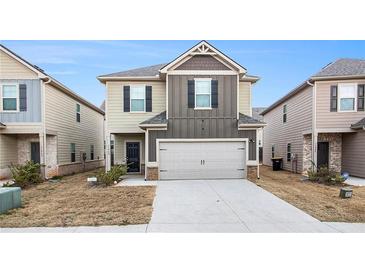 Two-story home showcasing neutral siding, complemented by a gray garage door and dark trim at 11948 Brightside Pkwy, Hampton, GA 30228
