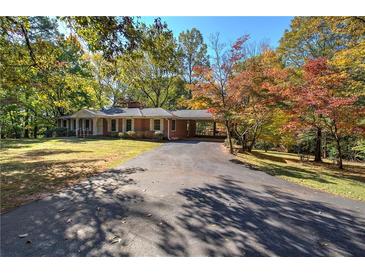 Brick ranch-style home with long driveway and carport surrounded by mature trees and fall foliage at 810 Mcconnell Rd, Powder Springs, GA 30127