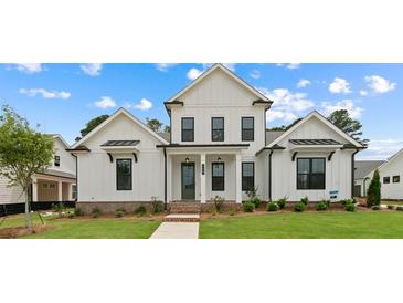 Two-story farmhouse with white siding, brick accents, and a landscaped lawn at 509 Pearl St, Cumming, GA 30040