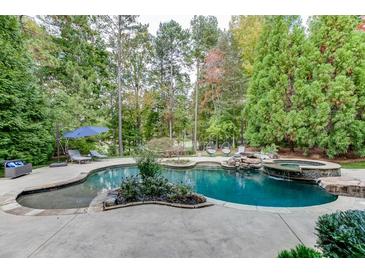 Beautiful backyard pool with waterfall feature, surrounded by lush landscaping and mature trees at 879 Big Horn Hollow, Suwanee, GA 30024