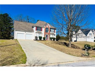 Charming two-story home featuring a two-car garage, manicured lawn, and a long driveway on a sunny day at 2717 Kristen Ct, Conyers, GA 30012