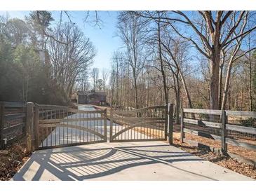 Long driveway with metal gates leading to a modern home nestled in woods at 600 Jones Rd, Roswell, GA 30075