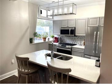 Modern kitchen featuring gray cabinets, stainless steel appliances, and a stylish countertop island at 2479 Peachtree Ne Rd # 105, Atlanta, GA 30305