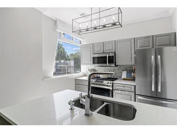 Modern kitchen features stainless steel appliances, gray cabinetry, a backsplash, and a quartz countertop at 2479 Peachtree Ne Rd # 105, Atlanta, GA 30305