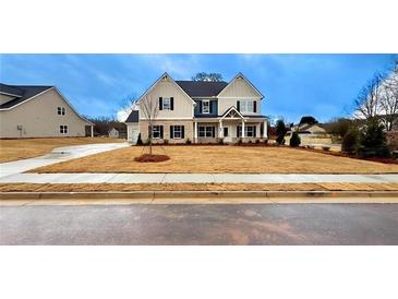 Two-story house with a beige exterior, blue accents, and a well-manicured lawn at 1451 Stephens View Dr, Loganville, GA 30052