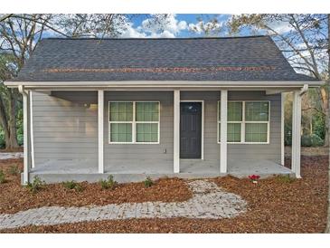 Charming gray cottage-style home with a welcoming front porch and gray roof, surrounded by trees and landscaping at 1815 River Ne St, Conyers, GA 30012