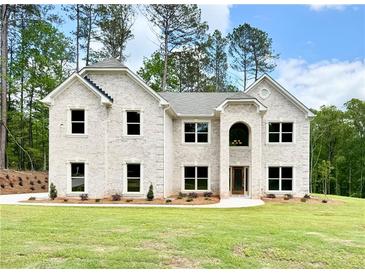 Stately two-story home featuring a light brick facade, a well-manicured lawn, and surrounded by mature trees at 5380 Deer Run Dr, Conyers, GA 30094