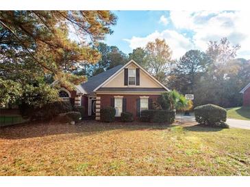 Charming brick home with manicured landscaping and a basketball hoop in the driveway at 210 Huiet Dr, Mcdonough, GA 30252