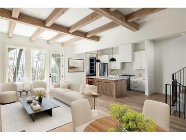 Bright, open-concept living room featuring wood beams, hardwood floors, and modern kitchen with island at 10939 Serenbe Ln, Chattahoochee Hills, GA 30268